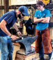 A farrier works on a shoe with an anvil. 